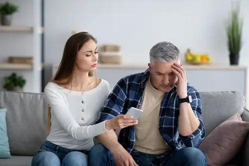 Adultery Concept, Woman Confronting Cheating Husband With Cell Phone Text Messages