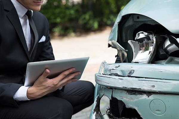 an accident reconstructionist examines a wrecked car