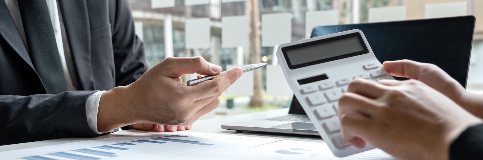 A professional is showing a calculator to a client while reviewing financial documents, seeking private investigator help for a suspected elder fraud case.