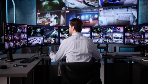 A man looking at screens represents surveillance services being provided for a client.