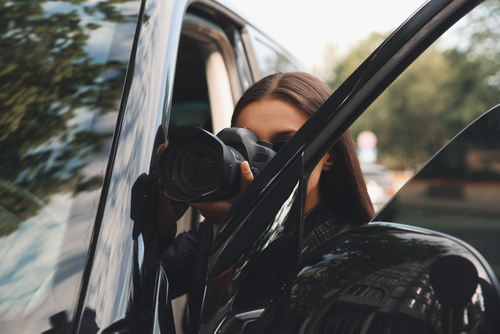 An adultery investigator takes a picture to collect evidence during the daytime.
