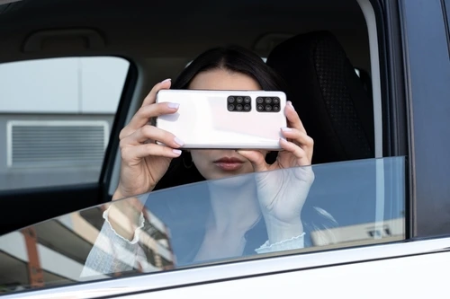 A woman uses a phone to take pictures for diy surveillance.