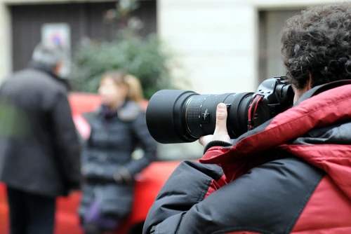 A private investigator photographs a couple on the street to prove cheating.